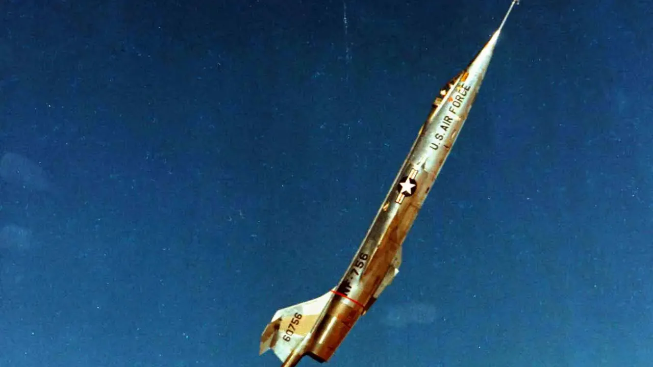 En Lockheed NF-104A stiger stejlt mod en blå himmel med en synlig flamme bag flyet.