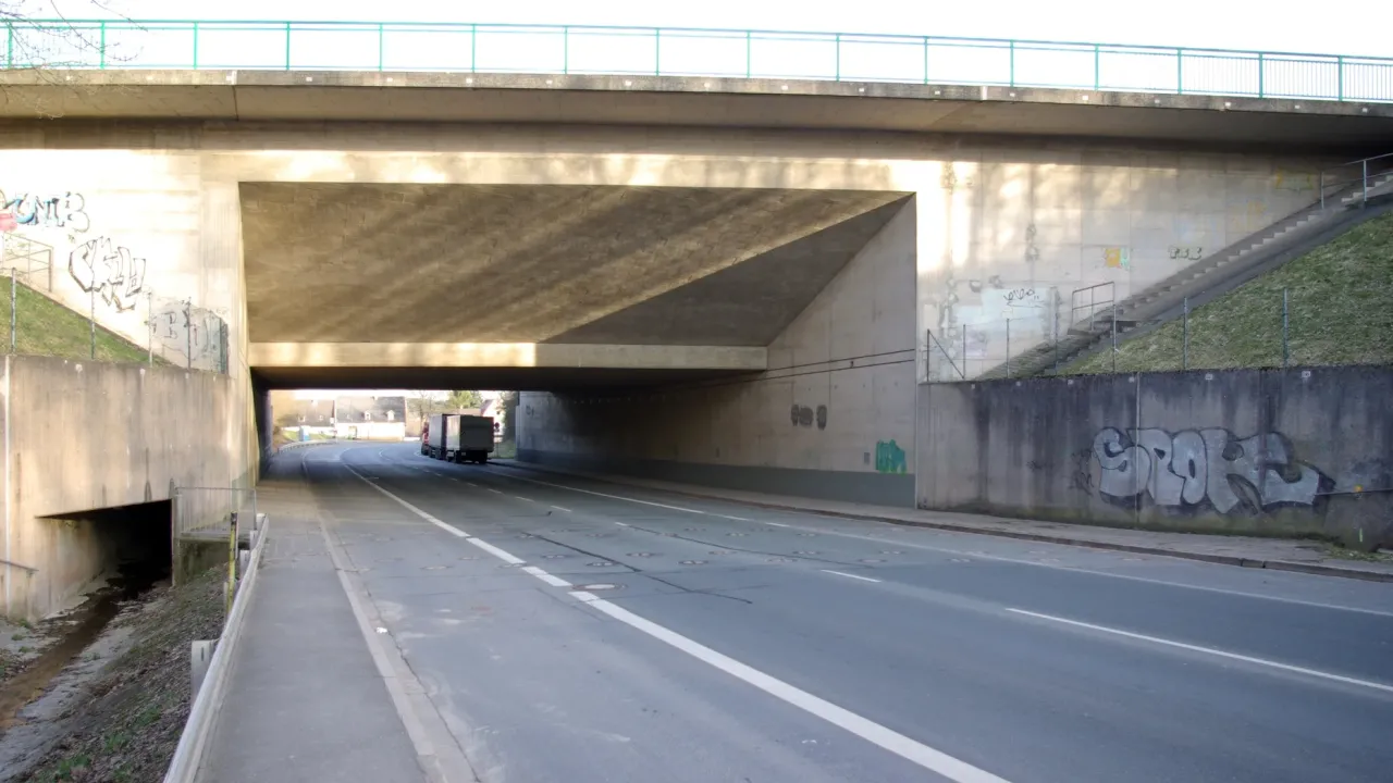 En vej under Main-Donau-Kanalen med rækker af små dæksler i asfalten.