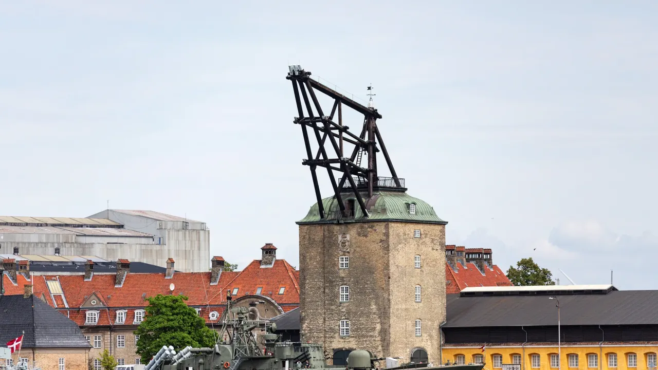 Mastekranen på Nyholm med murværk, grønt tag og den fritstående tømmerkonstruktion over taget, fotograferet fra havnen.