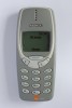 Grå Nokia 3310 med lille skærm og fysiske taster, fotograferet forfra.