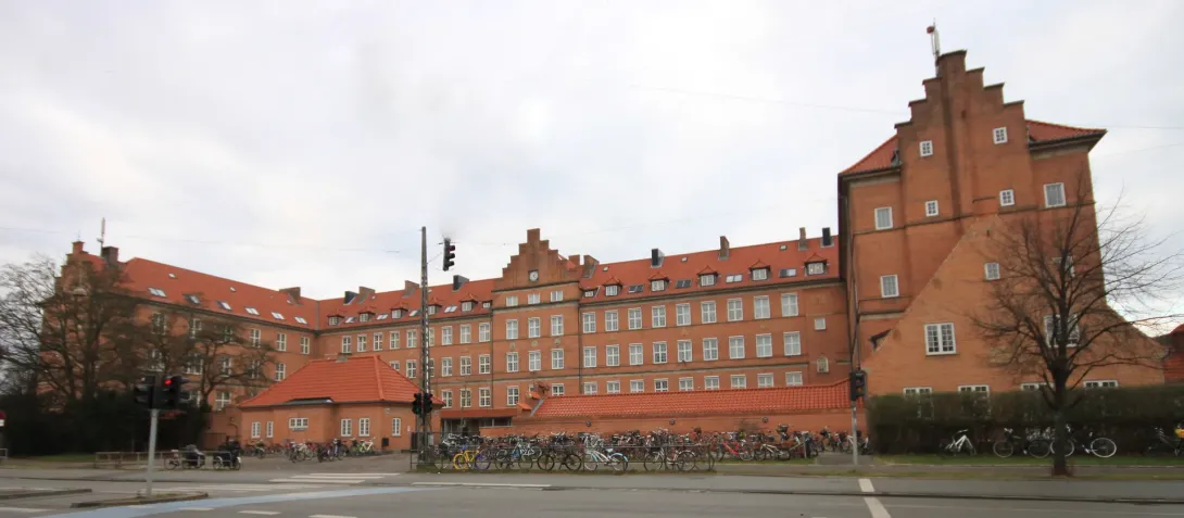Nyboder Skoles lange røde murstensfacade med cykler langs Øster Voldgade i København.