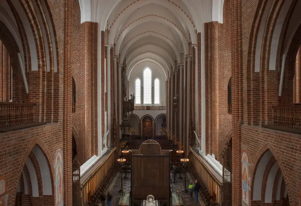Roskilde Domkirkes høje kirkerum med røde teglstenssøjler og lyse hvælv.