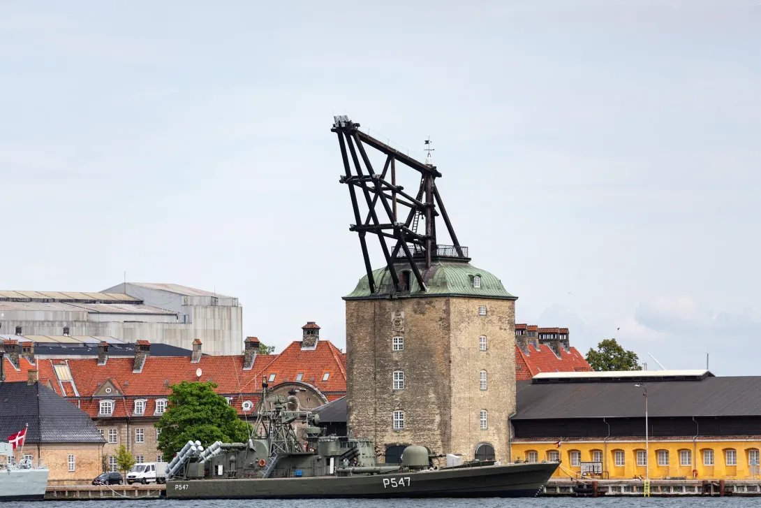 Mastekranen på Nyholm med murværk, grønt tag og den fritstående tømmerkonstruktion over taget, fotograferet fra havnen.