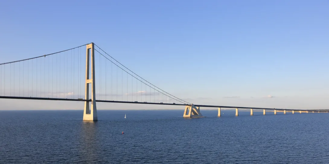 Storebæltsforbindelsens østbro i lavt sollys med en høj pylon og vejbanen over havet.